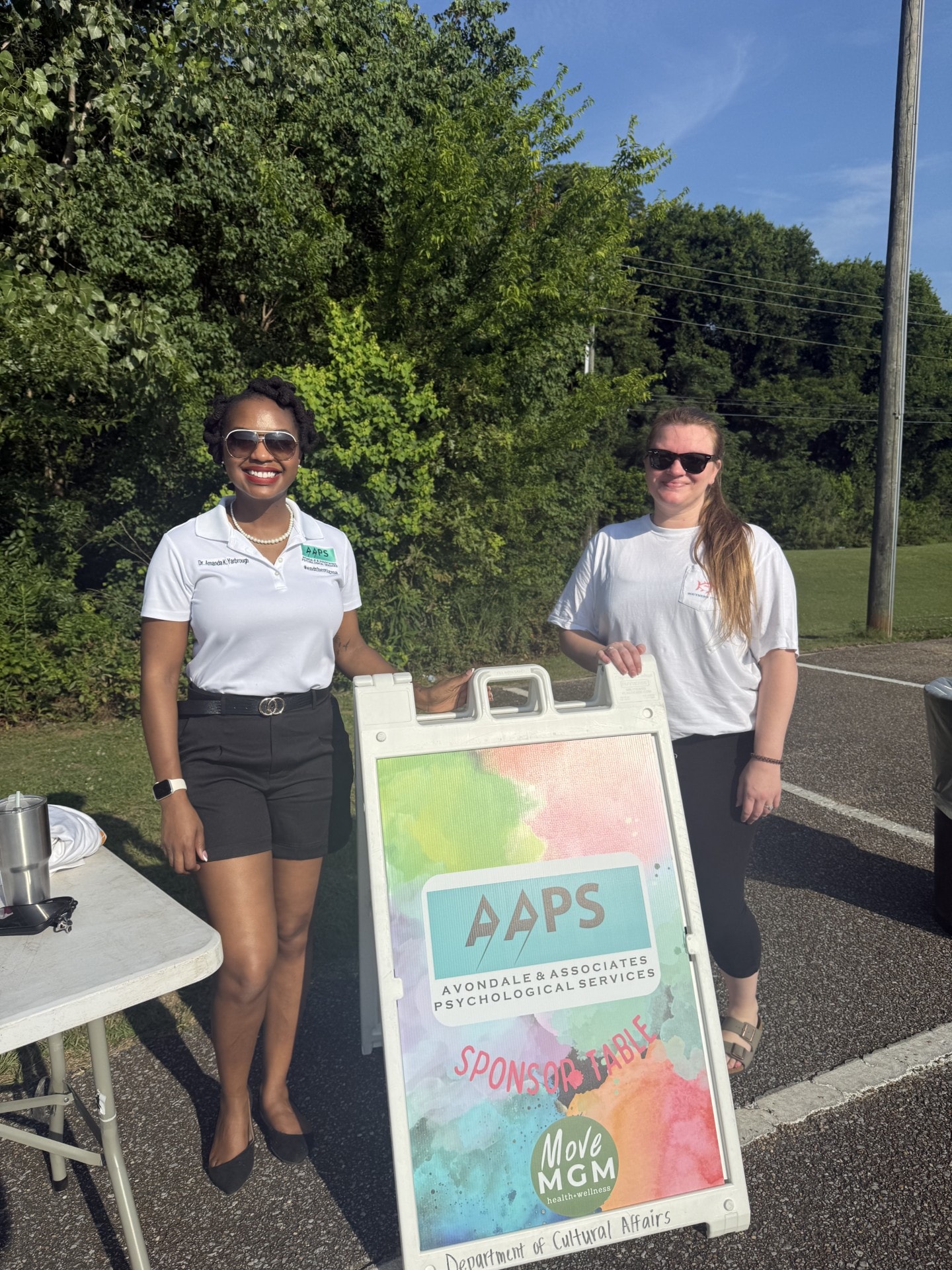 Dr. Amanda Lewis-Yarbrough and team member at AAPS sponsor table outdoors
